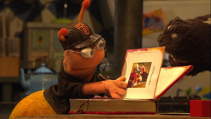 Finchen leiht sich von Wolle und Pferd das tolle Märchenbuch, das sie immer zum Einschlafen lesen. – Bild: NDR/​Sesame Workshop