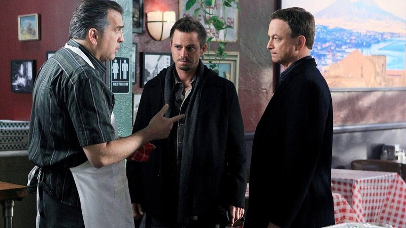 Die Ermittlungen führen Detective Mac Taylor (Gary Sinise, r.) und Danny Messer (Carmine Giovinazzo, M.) in eine Pizzeria. Dort befragen die Ermittler den Onkel des Opfers, Ray Tortucci (Daniel Roebuck). – Bild: TVNOW /​ CBS