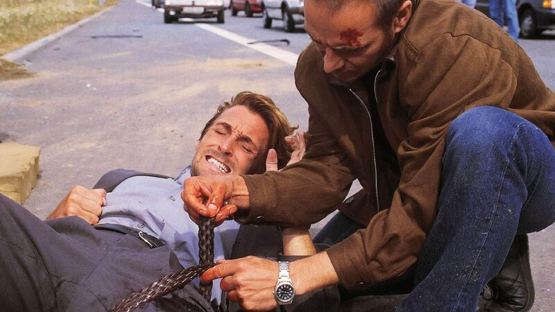 Auf Semirs Auto ist geschossen worden. Andre (Mark Keller, lieg.) wurde dabei schwer verletzt. Semir (Erdogan Atalay) weiß noch nicht, daß der Anschlag eigentlich ihm galt … – Bild: TVNOW