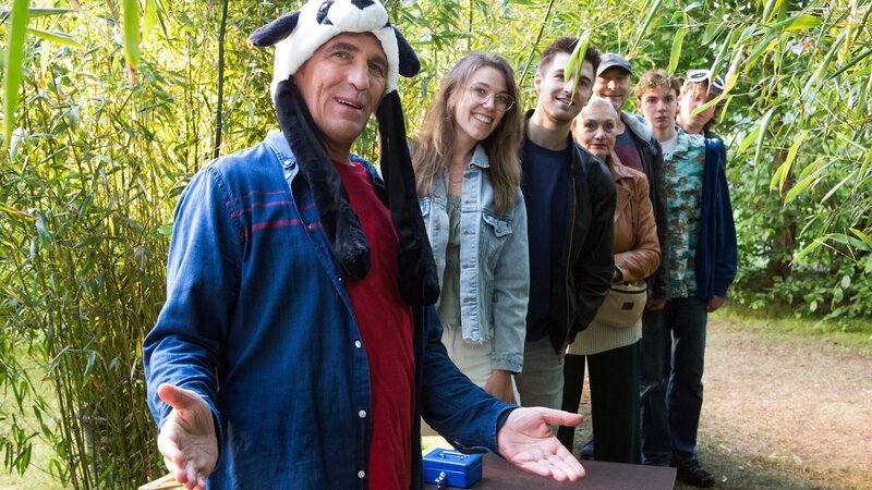 Die Ausstellung ist eröffnet! Fritz Fuchs (Guido Hammesfahr) empfängt die ersten Gäste seiner Panda-Ausstellung und zeigt ihnen neben unzähligen Bambuspflanzen auch Panda-Fotos und Videos seiner Chinareise. – Bild: ZDF und Zia Ziarno