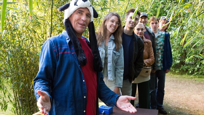 Die Ausstellung ist eröffnet! Fritz Fuchs (Guido Hammesfahr) empfängt die ersten Gäste seiner Panda-Ausstellung und zeigt ihnen neben unzähligen Bambuspflanzen auch Panda-Fotos und Videos seiner Chinareise. – Bild: ZDF und Zia Ziarno