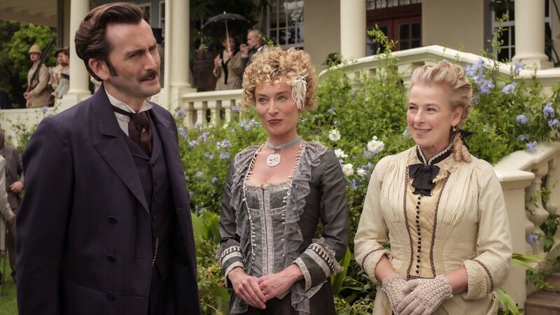 Auf einer Gartenparty, die die Frau des britischen Gouverneurs von Hongkong, Lady Clemency (Victoria Smurfit, M.), Fogg zu Ehren veranstaltet, steht Phileas Fogg (David Tennant, l.) im Zentrum vor allem des weiblichen Interesses. – Bild: ZDF and Graham Bartholomew