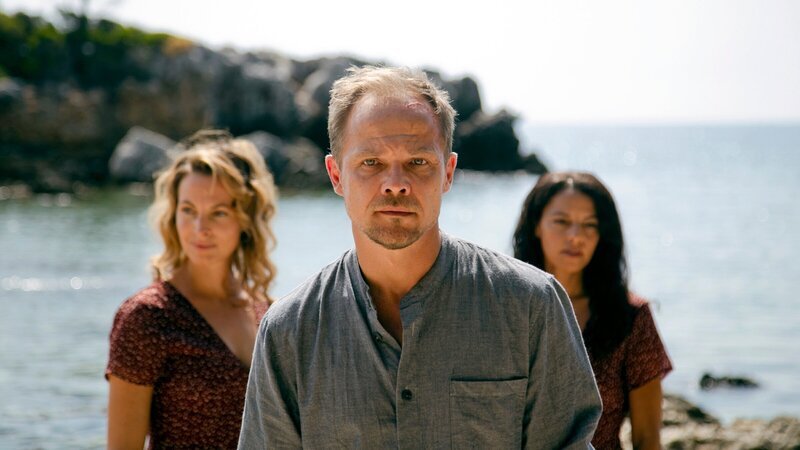 Privatdetektiv Hartwig Seeler (Matthias Koeberlin, Mitte) trifft in Griechenland auf Sarah (Petra Michelle Nérette, re.) – und auf Erinnerungen an seine verstorbene Frau Maria (Dagny Dewath, li.). – Bild: ZDF und ARD Degeto/​Nikos Katsaros