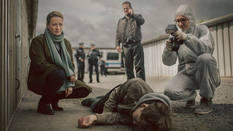 Dr. Theresa Wolff (Nina Gummich, l.), Bruno Lewandowski (Aurel Manthei, M.) und die Spurensicherung (Komparsin, r.) verschaffen sich einen Eindruck von dem Tatort und der Leiche (Philip Günsch, liegend). – Bild: ZDF und ADRIAN GROSS