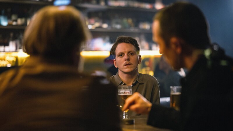 Audun (Jonas Strand Gravli, M.) fühlt sich bei den regelmäßigen Treffen mit seinen ehemaligen Mitstudenten (Komparsen) fremd und träumt von einem Ausbruch aus der Enge seines derzeitigen Lebens. – Bild: ZDF und LUKAS SALNA