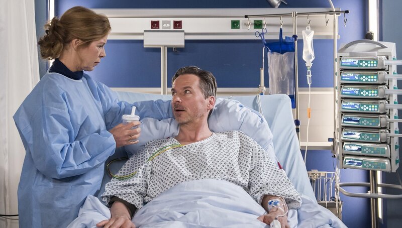 Noch immer suchen die Ärzte nach der Infektion, die bei Frank Wöhlitz (David C. Bunners, r.) für das Fieber sorgt. Bis dahin kümmert sich seine Frau Martina (Marion Kracht, l.) liebevoll um ihn. – Bild: Jens-Ulrich Koch
