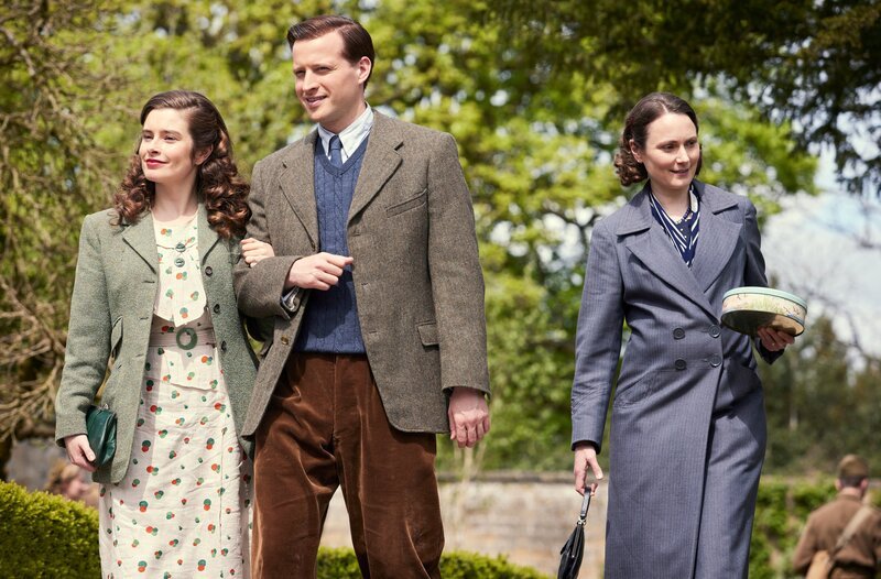 Helen Herriot (Rachel Shenton, li.) und James Herriot (Nicholas Ralph, mi.) besuchen gemeinsam mit Mrs. Hall (Anna Madeley, re.) eine Gartenparty zu Ehren der Rekruten. – Bild: WDR/​Playground & All3Media International