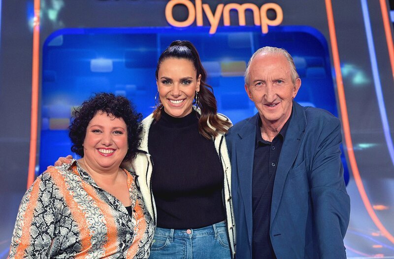 Moderatorin Esther Sedlaczek (M.) mit den Kandidaten des Teams „Comedy“: Meltem Kaptan (l.) und Mike Krüger (r.) – Bild: ARD/​ITV Studios