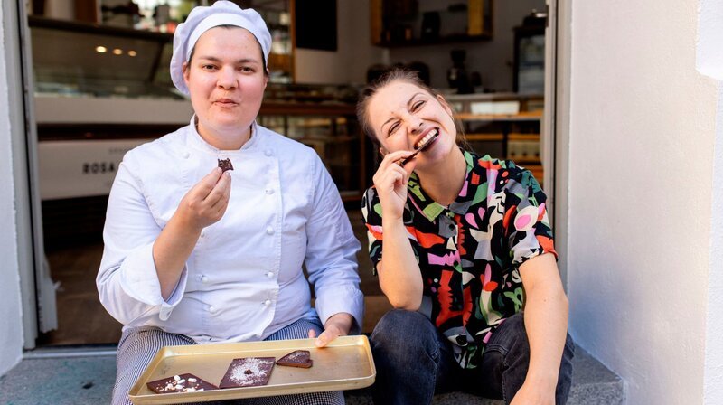 Marina und die Schokoladenmacherin Friederike verkosten ihre selbstgemachte Checkerin-Schokolade. – Bild: BR/​megaherz gmbh/​Hans-Florian Hopfner