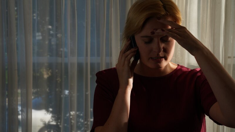 Recre of Kristine talking on phone with one hand on her forehead. – Bild: Warner Bros. Discovery, Inc. or its subsidiaries and affiliates