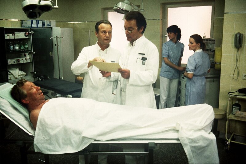 In Gestalt von Arthur Wilkens (Heinz Reincke, li.) ist ein seltsamer Patient in die Schwarzwaldklinik gekommen: Eine Mischung zwischen Landstreicher und fahrendem Gesell, – ein richtiger „Weltreisender“ (v.li.n.re.: Heinz Reincke, Karl Walter Diess, Klausjürgen Wussow). – Bild: ZDF und Thomas Waldhelm