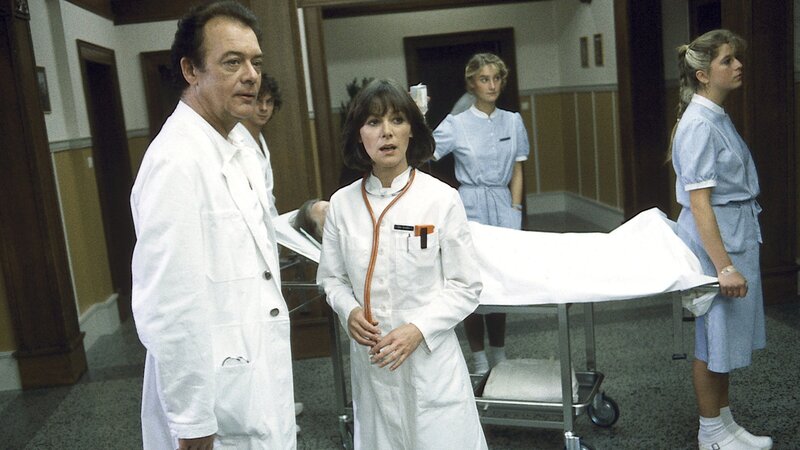 Dr. Elena Bach (Heidelinde Weis) gelingt es nicht, das alte Verhältnis zu Professor Brinkmann (Klausjürgen Wussow) wiederherzustellen. – Bild: ZDFneo