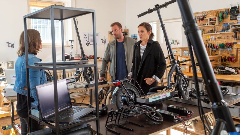 Die Kommissare Lars Pöhlmann (Dominic Boeer, M.) und Karoline Joost (Nike Fuhrmann, r.) informieren Greta Matthes (Lena Schmidtke, l.), die Geschäftsführerin des E-Scooter-Verleihs, über den Tod ihres Partners. – Bild: ZDF /​ Meyerbroeker