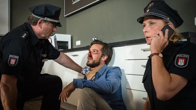 Hans (Bruno F. Apitz, l.) und Claudia (Janette Rauch, r.) kümmern sich um Christoph Chrom (René Geisler, M.), der in seiner Galerie niedergeschlagen wurde. – Bild: ZDF und Boris Laewen
