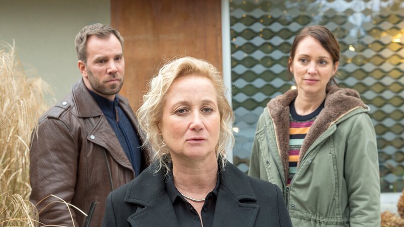 Miriam Walbeck (Iris von Kluge, M.), die Frau des Toten, kann sich absolut nicht vorstellen, dass ihr Mann eine heimliche Affäre mit einem jungen Mann gehabt hat. Und wozu hat er bloß eine Alibiagentur konsultiert? Kommissar Pöhlmann (Dominic Boeer, l.) und Kommissarin Joost (Nike Fuhrmann, r.) fragen sich: Was verbirgt die Frau? Hat sie von der Affäre ihres Mannes gewusst? Und wenn ja: Hat sie dann nicht ein eindeutiges Motiv, ihren Mann umzubringen? Sind die Kommissare auf der richtigen Spur? – Bild: ZDF /​ Meyerbroeker