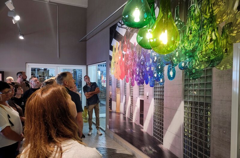 Besucher bestaunen die Designerleuchten der Glasmanufaktur, die auch im Kunstarchiv Zürich hängen. – Bild: MDR/​Tom Kühne