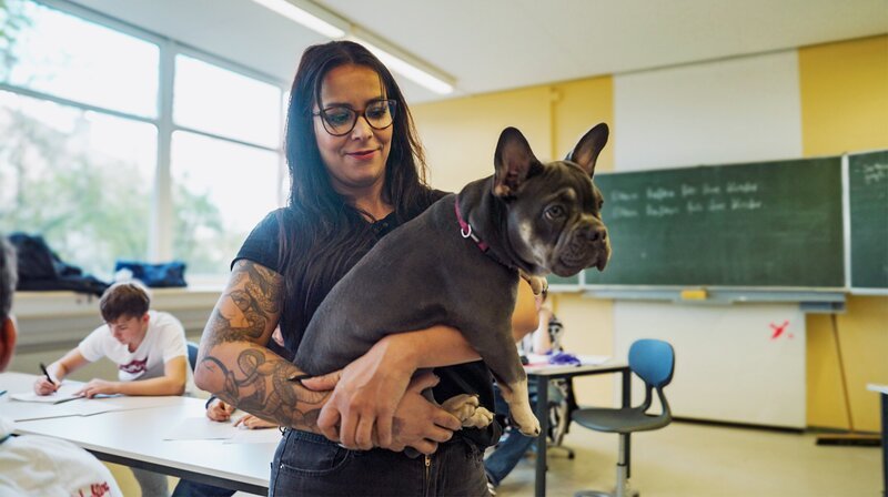 Lehrerin Julia Molter nimmt Hund Ruby mit in ihre besondere Klasse, wo keiner bisher auf dem herkömmlichen Weg einen Abschluss geschafft hat. Ruby hilft, mit den Schüler:innen noch schneller eine Verbindung aufzubauen. – Bild: SWR/Lars Reuther Lehrerin Julia Molter nimmt Hund Ruby mit in ihre besondere Klasse, wo keiner bisher auf dem herkömmlichen Weg einen Abschluss geschafft hat. Ruby hilft, mit den Schüler:innen noch schneller eine Verbindung aufzubauen. – Bild: SWR/Lars Reuther