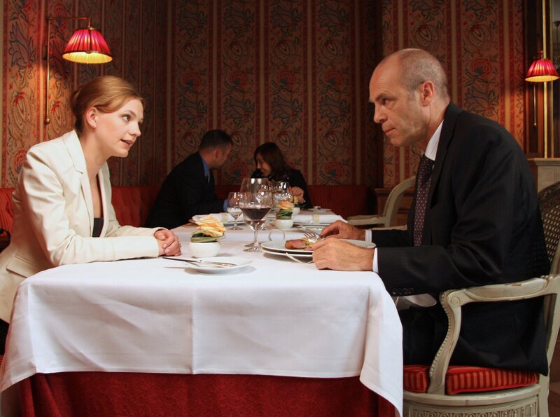 ARD GELD.MACHT.LIEBE – KOMPLOTT, Regie Christine Kabisch. Alexander Blessmann (Peter Kremer) ist sehr interessiert daran, was Ariane Sailer (Anna Bertheau) ihm zu sagen hat. – Bild: ARD Degeto/​Tivoli Film/​Flo Lackner