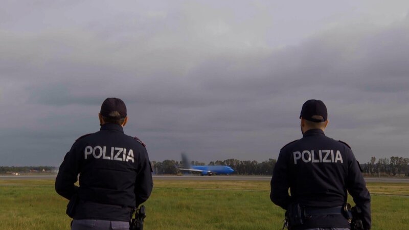 Landet hier gerade die nächste Schmuggelware? Zwei Beamte beobachten aufmerksam, wie ein Flieger auf dem Flughafen von Rom aufsetzt. – Bild: TV Alliance – TV A2 Media GmbH/​WeltN24 GmbH