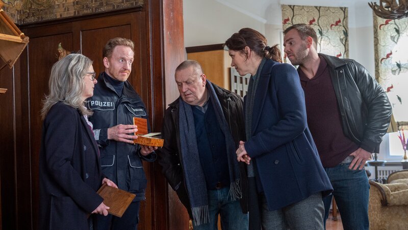Der Spieleerfinder Hans Neumann hat der Nachwelt ein rätselhaftes Gedicht hinterlassen, das auf einen Goldschatz hinweist. Doch ist dieser Schatz real oder nur eine Erfindung? Die Kommissare Reuter (Udo Kroschwald, M.), Joost (Nike Fuhrmann, 2.v.r.) und Pöhlmann (Dominic Boeer, r.) sind zunächst skeptisch. Doch Timmermann (Mathias Junge, 2.v.l.) lässt nicht locker und kommt Neumann mithilfe seiner Haushälterin Grischa Walter (Christiane Filla, l.) allmählich auf die Spur. – Bild: ZDF /​ Meyerbroeker