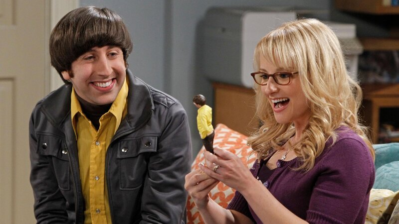 Howard (Simon Helberg, l.) zeigt Bernadette (Melissa Rauch, r.) seine neue Actionfigur und eine Actionfigur, die er aus ihr gemacht hat. – Bild: MAX Hungary