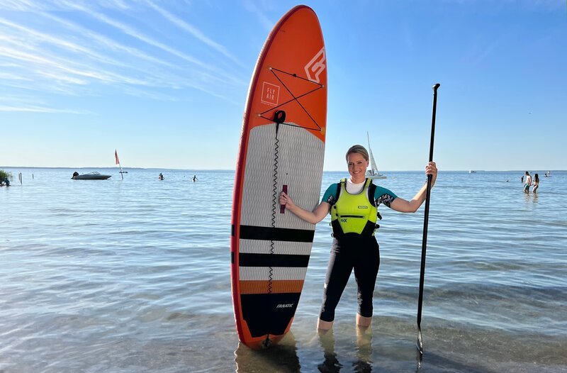 Judith Rakers probiert aus, wie sie auf einem Stand-up-Paddling-Board Yoga machen kann, ohne herunterzufallen. – Bild: WDR/​Bavaria