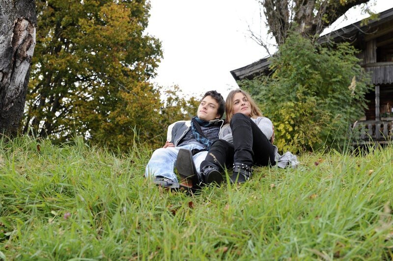 Wieder vereint und eng umschlungen sitzen Lilli (Ronja Forcher, r.) und ihr Freund Mario (Dominik Nowak) auf der Wiese hinter dem Gruberhof. – Bild: ZDF und Thomas R. Schumann