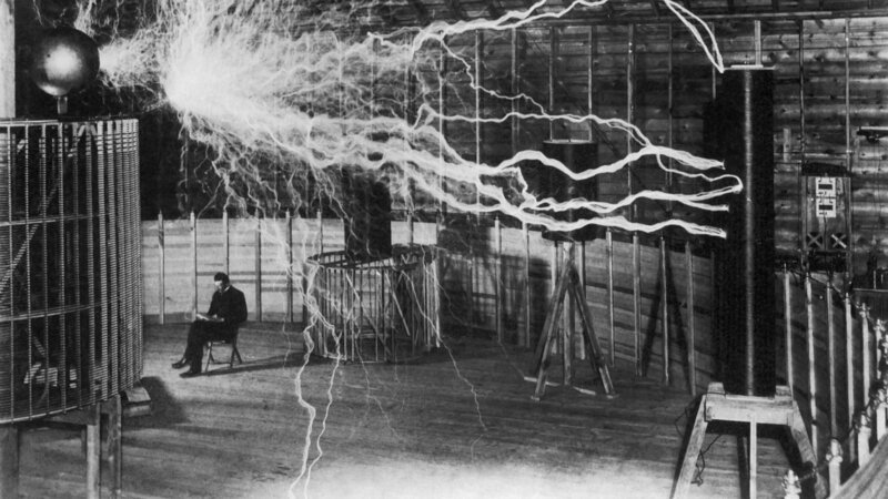 Erfinder und Wissenschaftler Nikola Tesla in seinem Labor, während sein Vergrößerungssender Hochspannungsgenerator Blitze von Elektrizität erzeugt. Dezember 1899. – Bild: John Parrot/​ Stocktrek Images /​ Getty Images /​ This content is subject to copyright.