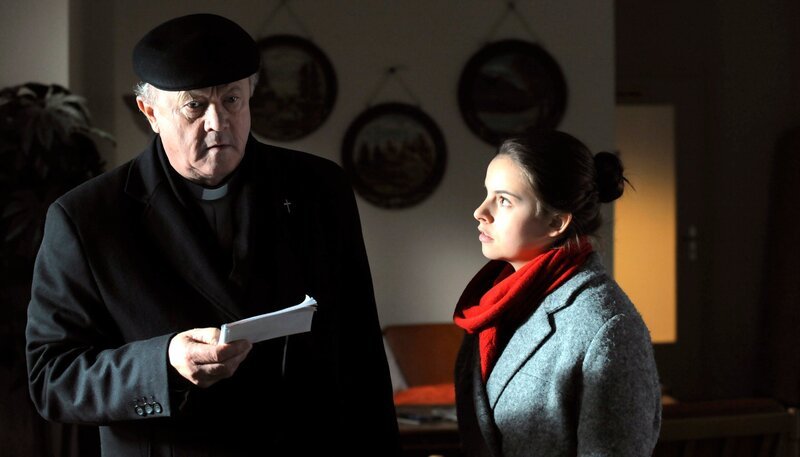 DAHOAM IS DAHOAM, Folge 1103, „Auf illegalem Grund“. Statt Amir finden Charlie und Pfarrer Kurz nur einen Zettel mit einer Nachricht vor. Von links: Pfarrer Kurz (Hans Stadlbauer) und Charlie Keller (Marie-Claire Schuller). – Bild: BR/​Marco Orlando Pichler