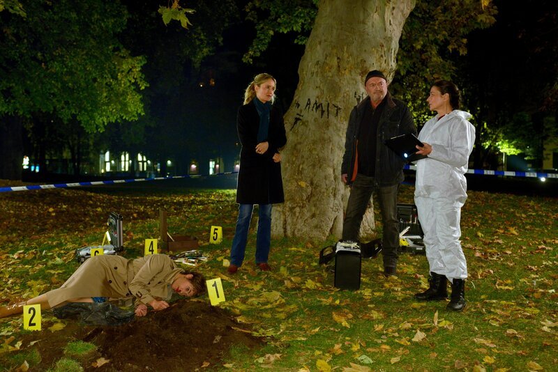 Linett Wachow (Stefanie Stappenbeck, 2. v. l.) und Otto Garber (Florian Martens, 2. v. r.) sowie die Rechtsmedizinerin Dr. Gabriele Simkeit (Eva Sixt, r.) sind am Tatort im Stadtpark und nehmen alle Spuren am Opfer Nadia Weihenheim (Hanna Jürgens, l.) auf. – Bild: ZDF/​ Katrin Knoke