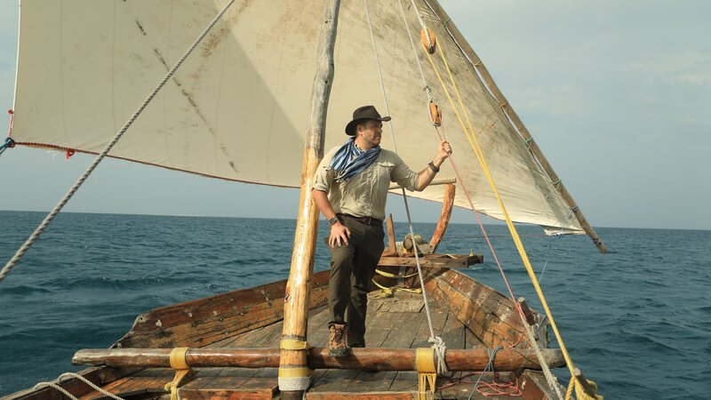 Gastgeber Josh Gates auf einem Segelboot vor der Küste von Sansibar, Tansania – Bild: Warner Bros. Discovery, Inc. or its subsidiaries and affiliates.