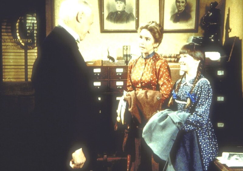 Laura Ingalls (Melissa Gilbert, M.), in Begleitung ihrer Nichte Jenny (Shannen Doherthy, r.), wird von dem Verleger Broxton (William Prince) empfangen, dem sie ihr Buch zur Beurteilung geschickt hat. – Bild: Sat.1 Gold