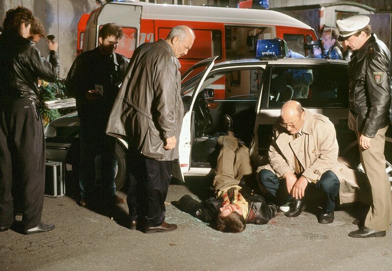 Erschüttert blicken die Kommissare Brockmöller (Charles Brauer, Mitte) und Stoever (Manfred Krug, 2.v.rechts) zusammen mit ihrem Kollegen Schwenke (Jürgen Morche, rechts) auf die Leiche des jungen Polizisten. – Bild: NDR