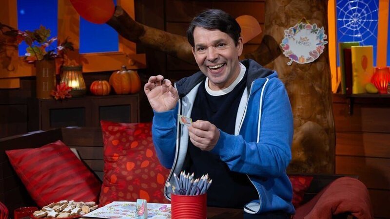 Es ist MACHMiT!-Woche im Baumhaus und Juri spricht lustige Zungenbrecher. Es zeigt das Wichtel-Brettspiel und die Karten mit weiteren Zungenbrechern. – Bild: KiKA