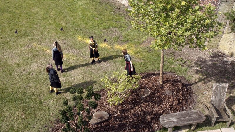 Mildred (Bella Ramsey, r.) ist mit Maude, Esther und Edith (Megan Hughes, Jenny Richardson und Tamara Smart, von links nach rechts) auf der Suche nach Esthers Vorfahrin, die angeblich schon mal einen Grundstein aufgeladen haben soll. Aus Esthers Familien-Stammbaum fliegen drei kleine Hexen-Vorfahrinnen heraus. – Bild: BBC/​ZDF Enterprises