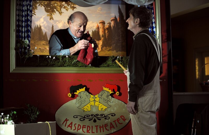 Pfarrer Kurz und Xaver machen sich Gedanken über die Zusammenarbeit der beiden Hauptdarsteller Theres und Alois. Von links: Pfarrer Vinzenz Kurz (Hans Stadlbauer) und Xaver (Michael Schreiner). – Bild: BR/​Marco Orlando Pichler