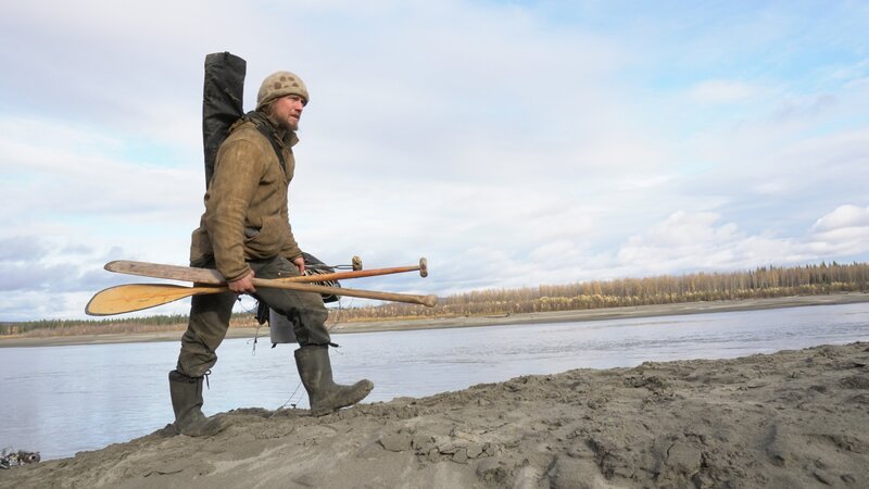 Gerrid walking along shoreline holding paddles. – Bild: Discovery Communications, LLC