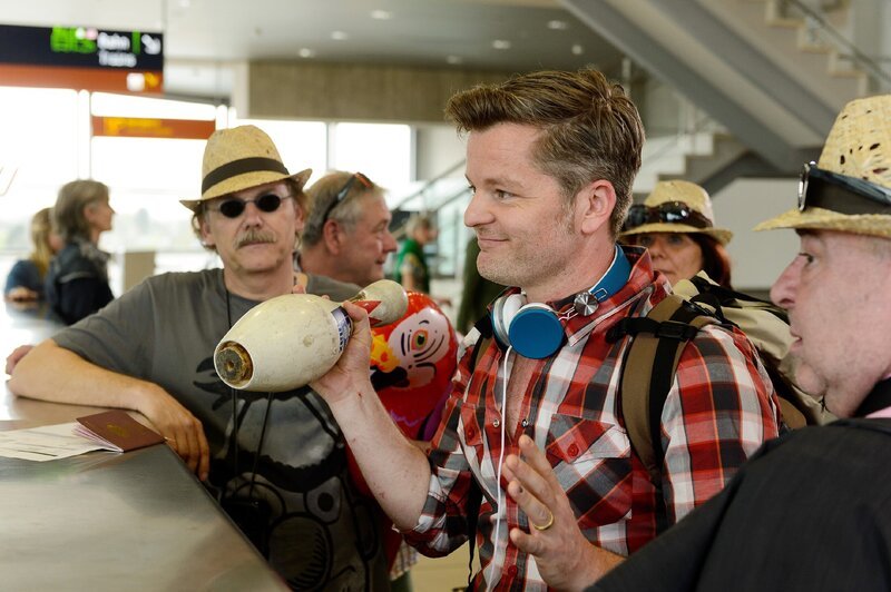 Ingo (Andre Dietz, M.) will die Verzögerung durch die Kegelgruppe (Komparsen) am Check-in-Schalter in den Griff bekommen. – Bild: RTL