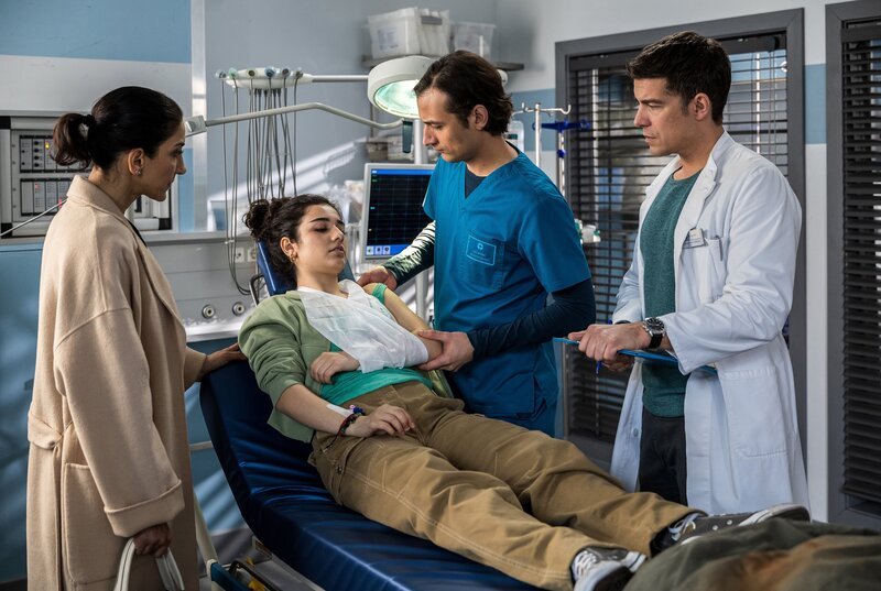 Ayra Nouri (Tanaz Molaei) wird von Dr. Ben Ahlbeck (Philipp Danne) und Assistenzarzt Ivo Maric (Jakob D’Aprile) in der Notaufnahme des JTK aufgenommen. Begleitet wird die junge Patientin von ihrer Mutter Dila Nouri (Saman Giraud). (v.l.n.r.: Saman Giraud, Tanaz Molaei, Jakob D’Aprile, Philipp Danne) – Bild: ARD/​Michael Kremer