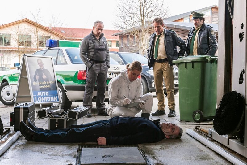 Als Hubert (Christian Tramitz, 2. von rechts) und Staller (Helmfried von Lüttichau, rechts) ihren Streifenwagen in der Waschstraße auf Hochglanz bringen wollen, kommt es zu einem unerwarteten Zusammenstoß mit einer Leiche. Der Tote ist Anton Lohfink (Komparse, liegend), der Besitzer der Waschstraße. Er hat sich mit einem Abschleppseil erhängt. Dr. Anja Licht (Karin Thaler) untersucht den Toten. Carl Hertl (Michael Lott, links) steht für erste Fragen der Polizisten zur Verfügung. – Bild: ARD/​ARD/​TMG/​Chris Hirschhäuser