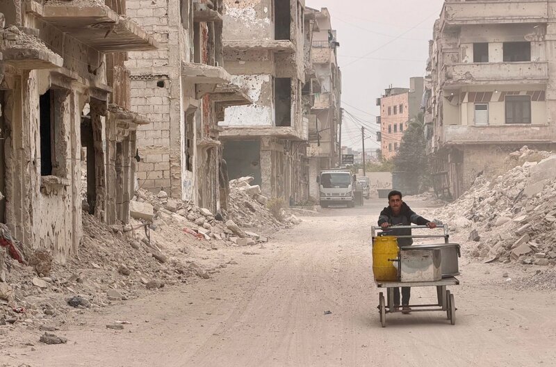 Ein Maisverkäufer im zerstörten Stadtviertel El Khaldiyye in Homs, unterwegs zwischen den Trümmern. – Bild: WDR/​Borhan Akid