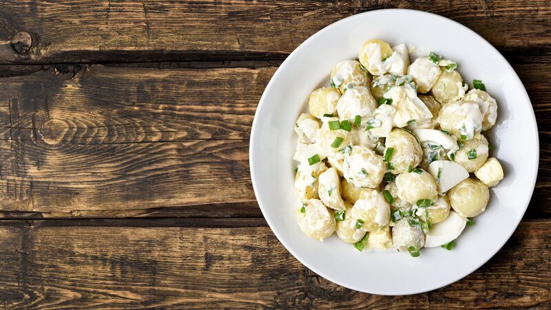 Potato salad with eggs and green onion on white plate over wooden background with copy space. Top view, flat lay food – Bild: Tatiana Volgutova