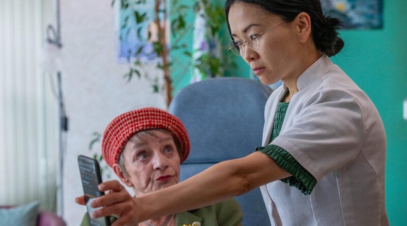 Die tiefenentspannte Frau Baumüller (Eva Weißenborn, li.) versteht, dass Jenny (Yvonne Yung Hee Bormann, re.) vom neuen Online-Buchungssystem gestresst ist. – Bild: ARD Degeto Fim/​UFA Fiction GmbH/​Oliver Vaccaro