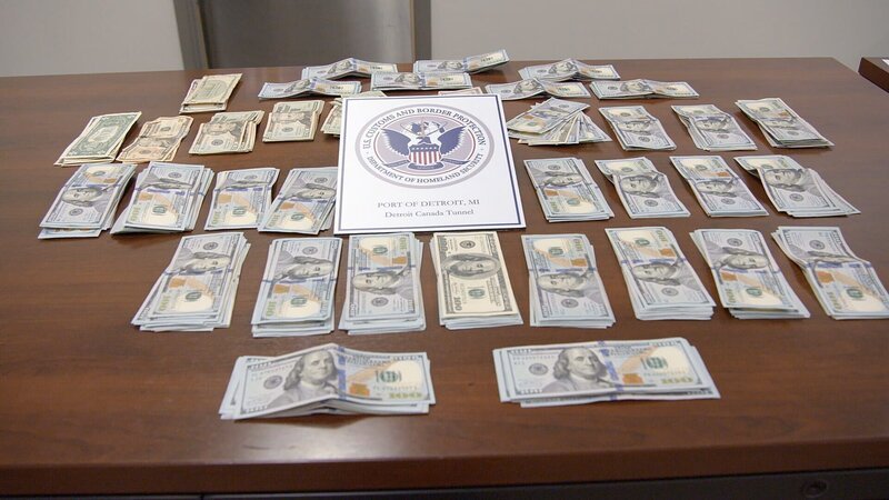 Mehrere Geldstapel werden auf einen Inspektionstisch gelegt, nachdem sie im Fahrzeug eines Verdächtigen entdeckt worden sind. (National Geographic) – Bild: National Geographic