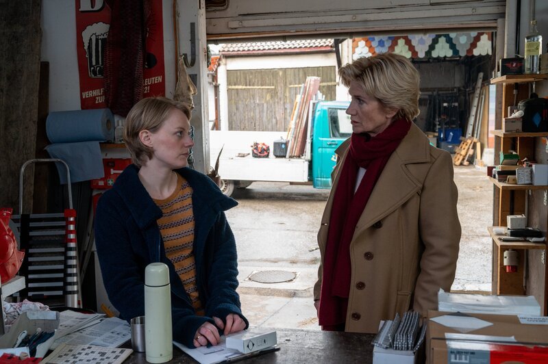 Nachdem die Leiche eines Dachdeckermeisters aufgefunden wurde, gerät dessen Ehefrau Marie Briem (Caroline Hellwig, l.) unter Tatverdacht. Der enge Kontakt zwischen ihr und einem zweiten Dachdeckermeister des Betriebs lässt die erste Kriminalhauptkommissarin Martina Seiffert (Astrid M. Fünderich, r.) vermuten, dass die beiden eine Affäre haben. – Bild: MARKUS_FENCHEL /​ ZDF