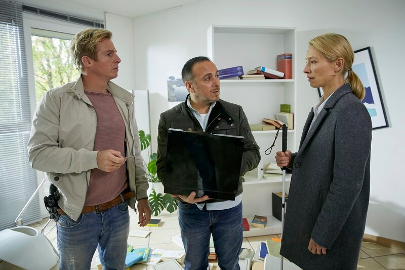 Paul (Daniel Roesner, l.) und Semir (Erdogan Atalay) stellen bei der Überprüfung der Wohnung des Mordopfers Markus Krohn fest, dass sie bereits durchsucht wurde. Die blinde Richterin Ingrid Seeler (Sandra Borgmann) findet den wichtigen Hinweis, der zeigt, dass das Mordopfer in einem Zeugenschutzprogramm lebte. – Bild: MG RTL D