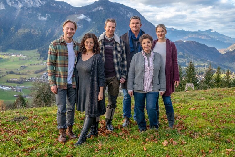 Mit Robert Schwarz (Timon Ballenberger, l.) und Anne (Ines Lutz, r.) erhält die Gruber-Familie rund um Lilli (Ronja Forcher, 2.v.l.), Lisbeth (Monika Baumgartner, 2.v.r.), Hans (Heiko Ruprecht, 3.v.l.) und Martin (Hans Sigl, 3.v.r.) „Zuwachs“. – Bild: ORF/​ZDF/​Erika Hauri