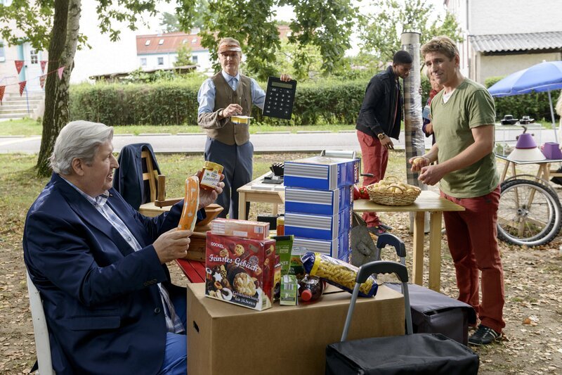 Sämtliche Banken haben wegen eines Computervirus kein Bargeld mehr. Fritz Fuchs (Guido Hammesfahr, r.) schlägt vor, dass die Bärstädter tauschen sollen wie auf den Märkten früher. Nachbar Paschulke Helmut Krauss, l.) neigt dazu die anderen übers Ohr zu hauen. Ordnungsamtmann Kluthe (Holger Handke, hinten Mitte). – Bild: ZDF/​Antje Dittmann