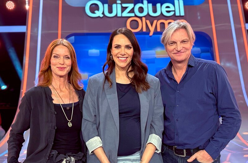 Moderatorin Esther Sedlaczek (M.) mit den Kandidaten des Teams „Schauspiel“: Esther Schweins (l.) und Stefan Jürgens (r.) – Bild: ARD/​ITV Studios