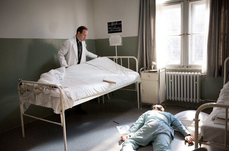 Max De Crinis (Lukas Miko, l.) wirft Hans von Dohnanyi (Max von Pufendorf, r.) aus dem Klinikbett und läßt ihn von der NS-Justiz abtransportieren. – Bild: ARD/​Julie Vrabelova